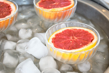 Pink grapefruit halves in glass bowls on ice