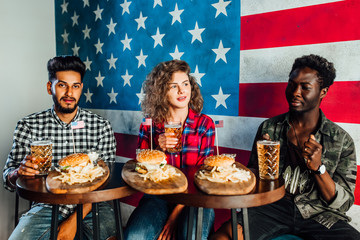 Enjoying burger and friends company at pub - Group of millennial friends spending quality time together at restaurant eating hamburgers..