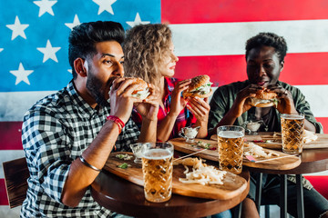Leisure, eating, food and drinks, people and holidays concept - smiling friends having dinner and drinking beer  and eat burgers at restaurant or pub.Cheeling time.