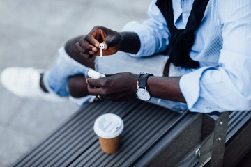 Close up photo. Man holding headphones, cup with coffe or tea on the stairs.