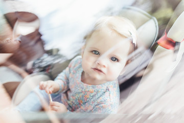 Fototapeta premium Cute little child girl sitting in safety seat inside car. Danger prevention.