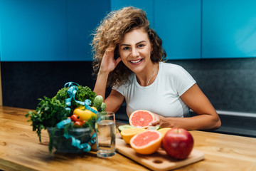 Woman on a  keto diet. Healthy and proper food with salad and dairy product on wooden table. Fruit in hand.