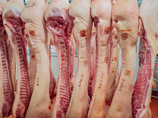 Processed meat carcasses hanging on hooks. Pork ready for processing. Meat workshop of specialized supermarket. Own production
