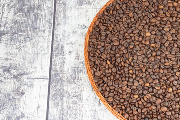 coffee grains in wicker plate on wooden background