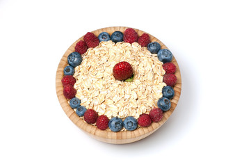 Breakfast cereal with blueberry, raspberry and strawberry in wooden bowl over white background. Top view.