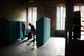 Dramatic wide angle view of two women in shabby changing room in sports club , copy space