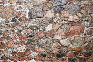 Gray concrete wall with uneven cracked stones. Shiny grunge rocky blocks wall.