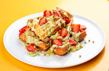 Belgian waffles with pistachio cream topping and strawberries