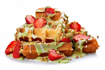 Belgian waffles with pistachio cream topping and strawberries. On white background