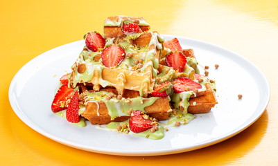 Belgian waffles with pistachio cream topping and strawberries