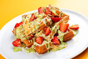 Belgian waffles with pistachio cream topping and strawberries