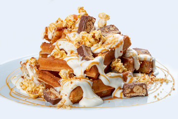 Belgian waffles with caramel topping, chocolate bars and popcorn.