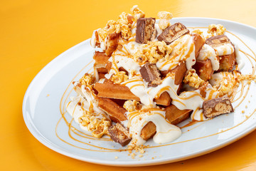 Belgian waffles with caramel topping, chocolate bars and popcorn.