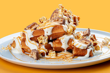 Belgian waffles with caramel topping, chocolate bars and popcorn.