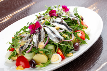 Salad with sprat, boiled potatoes, egg, cucumbers and arugula.