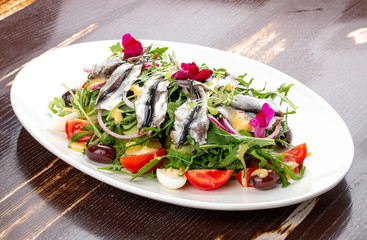 Salad with sprat, boiled potatoes, egg, cucumbers and arugula.