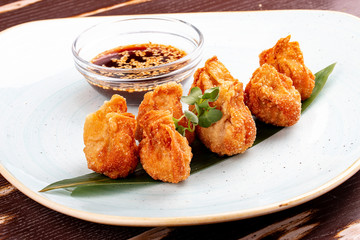 Fried wontons with soy sauce served on a bamboo leaf.