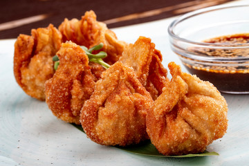 Fried wontons with soy sauce served on a bamboo leaf.