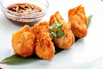 Fried wontons with soy sauce served on a bamboo leaf.