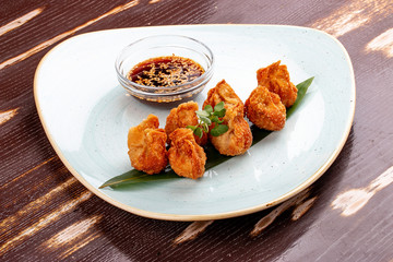 Fried wontons with soy sauce served on a bamboo leaf.