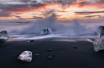 Waves crahshing against Ice at Diamond beach during sunrise- Iceland - Winter