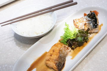 grilled Saba fish and Salmon fish sauce with white rice and brown chopsticks on table. Japanese food.