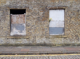 front view of an old abandoned derelict house on an empty street with boarded up windows and...