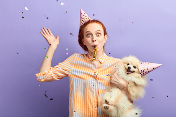 excited ginger girl has positive time at party. close up portrat, isolated blue background, studio...