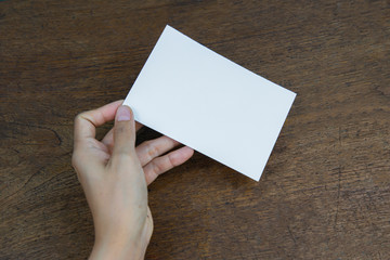 Obraz premium A6 Flyer / Postcard / Invitation Mock-Up - hands holding a blank flyer on a on a wooden table background.
