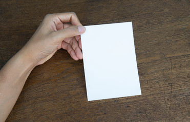 A6 Flyer / Postcard / Invitation Mock-Up - hands holding a blank flyer on a on a wooden table background.