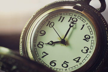 Closeup pocket watch on table and sunlight. At 8 am. o'clock in the morning. Concept of starting work today.