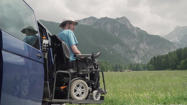 4k resolution video of A man on wheelchair going out of a car on electric lift specialized vehicle for people with disabilities. Self help for disabled people concept