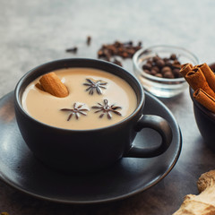 Masala tea. Traditional indian chai in black cup with spiced on grey background