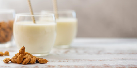 Almond milk in glasses with almond on a light wooden table