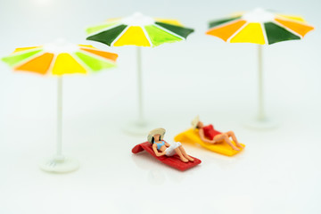 Miniature people: Tourists Sunbathing on the beach. Summer Concept.