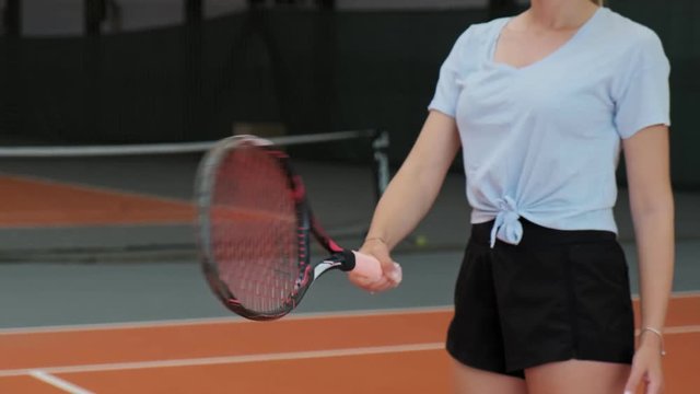 Pretty woman bounce tennis ball with racket. Close-up view of young female doing keepy-uppies with tennis ball