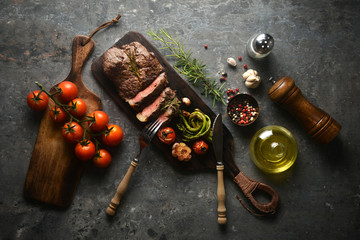 Meat steak serving on wooden butcher board with various ingredients surrounding,with fork and knife.top view, horizontal image.