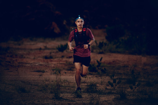 trail runner wearing headlamp running on the rocky road in the night