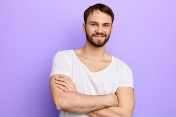 young strong caucasian man standing with crossed arms, looking at the camera,muscular guy expresses positive feeling . close up portrait. studio shot, body care, health care