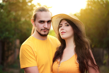 A man and a young woman in bright yellow clothes on a village street. A couple in love, summer, hot day, bright colors.