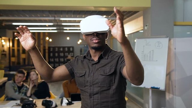 Young concentrated man in virtual reality VR glasses working in the office.