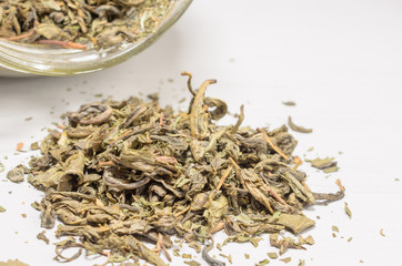 dried green tea leaves on wooden background