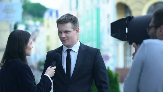Smiling politician giving interview to TV journalist, operator recording live