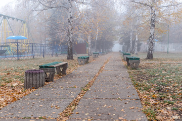Benches in an old abandoned amusement park on a foggy autumn morning