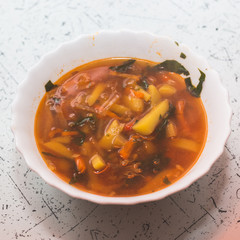 Traditional Ukrainian dish in a white plate on the table - borsch