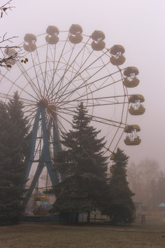 Ferris wheel in an old abandoned park in the autumn in thick fog