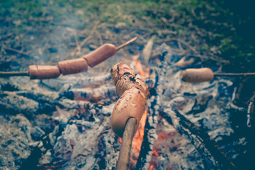 Cooking fried sausages on a fire in the forest