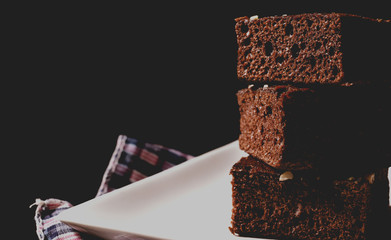 Close up chocolate brownies on white dish and hard light on black background