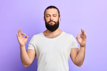 handsome relaxed young man, with closed eyes , in meditation zen mode, isolated blue background. Stress relief techniques. close up portrait. man reducing stress. hobby, lifestyle, free time