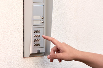 The hand of a young woman enters a numeric code on the keypad of an electronic lock